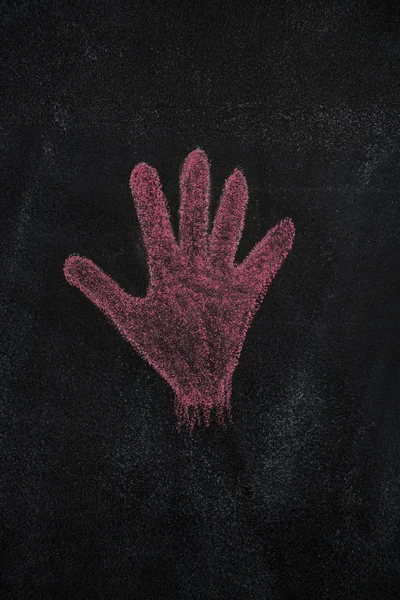 Red hand shape on black chalkboard
