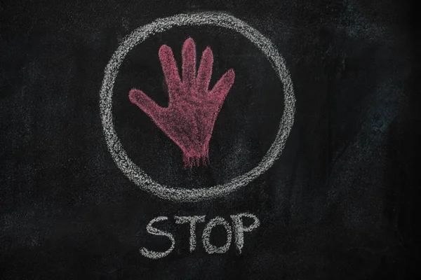 Vörös kéz alak és a stop szó a kört a fekete chalkboard — Stock Fotó