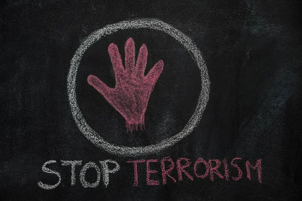 Forma de la mano roja y detener el texto del terrorismo en el círculo sobre pizarra negra — Foto de Stock