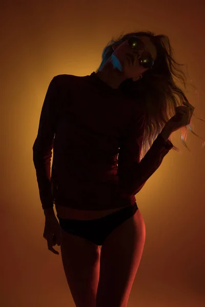 Женский силуэт над оранжевой светлой стеной студии — стоковое фото