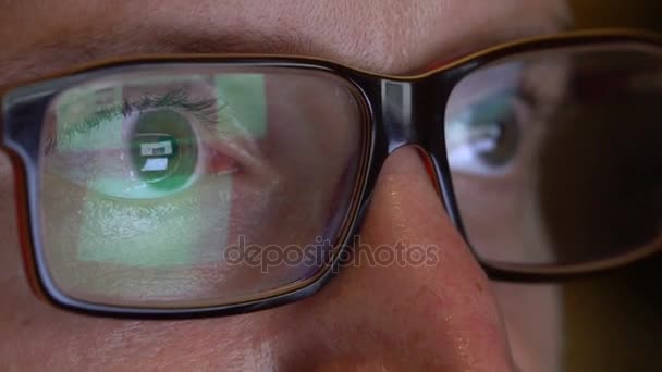 Closeup man's eyes in glasses works on laptop at night — Stock Video