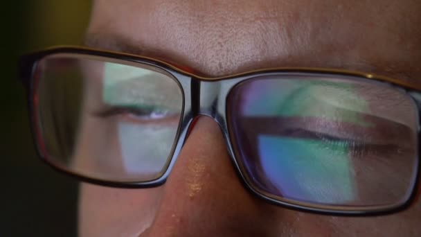 Closeup man's eyes in glasses works on laptop at night — Stock Video