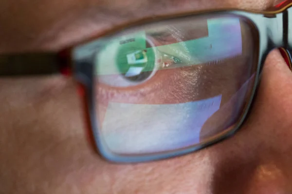 Zbliżenie człowiek oczu w okularach działa na laptopie w nocy — Zdjęcie stockowe