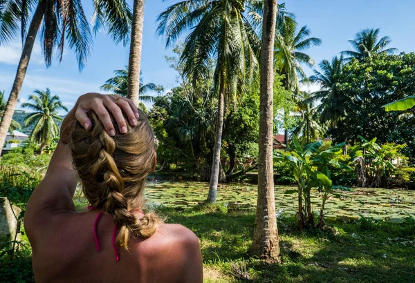 Mulher olhando para a bela vista tropical com palmeiras e pequena lagoa — Fotografia de Stock