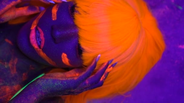 Mujer sexy con cara fluorescente UV y maquillaje corporal — Vídeos de Stock