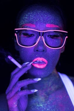 Closeup woman face with fluorescent make up smoking cigarette, creative makeup look great for nightclubs. Halloween party, shows and music concept clipart