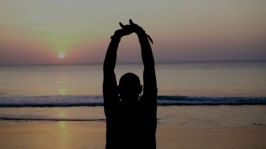 Arkadan görünüşü hava kadar silah ile sahilde sırasında güzel günbatımı - yavaş hareket video adam ayakta