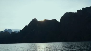 Tropikal bir göl, dağlar, uçurumlar ve kayalar su yüzeyine günbatımı arka plan, Khao Sok Milli Parkı, Surat Thani, Tayland - video yavaş tekne gezisine