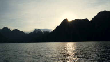 Tekne gezisine tropikal bir göl, dağlar, uçurumlar ve kayalar su yüzeyine günbatımı arka plan, Khao Sok Milli Parkı, Surat Thani, Tayland 
