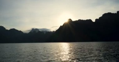 Tekne gezisine tropikal bir göl, dağlar, uçurumlar ve kayalar su yüzeyine günbatımı arka plan, Khao Sok Milli Parkı, Surat Thani, Tayland 
