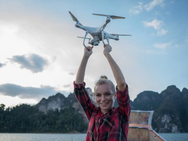 Drone tropikal kireçtaşı kayalıklarla ve gün batımı arka plan üzerinde tutarak kaldırdı elleriyle ahşap long tail tekne içinde oturan kadın