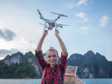 Drone tropikal kireçtaşı kayalıklarla ve gün batımı arka plan üzerinde tutarak kaldırdı elleriyle ahşap long tail tekne içinde oturan kadın