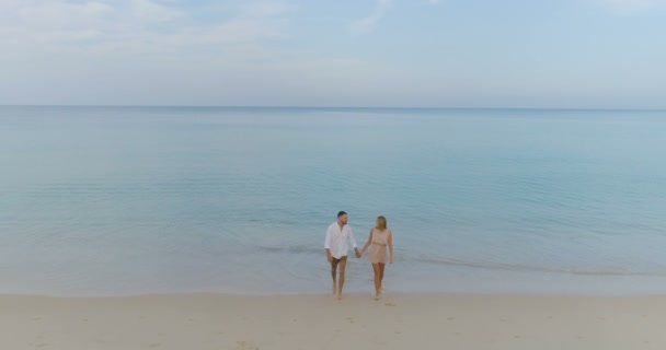 海と空の背景 スローモーションでビデオの上熱帯の砂浜の上を歩いて美しいカップルの航空写真 — ストック動画