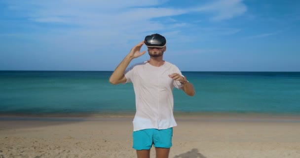 年轻男子使用虚拟现实玻璃在热带海滩上空美丽的海和天空背景 — 图库视频影像