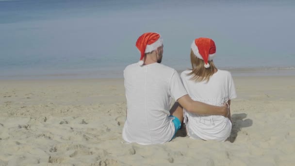 圣诞节美丽的海滩情侣戴着圣诞老人的帽子在夏天的阳光下在热带旅游目的地的旅游假期在冬季假期 视频慢动作 — 图库视频影像