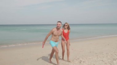 Frizbi uçan disk ile güneşli yaz gün - ağır çekimde video boyunca sahilde oynarken mutlu çift