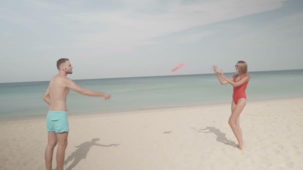快乐的情侣玩飞盘飞行光盘在海滩上 在阳光明媚的夏日 — 图库视频影像