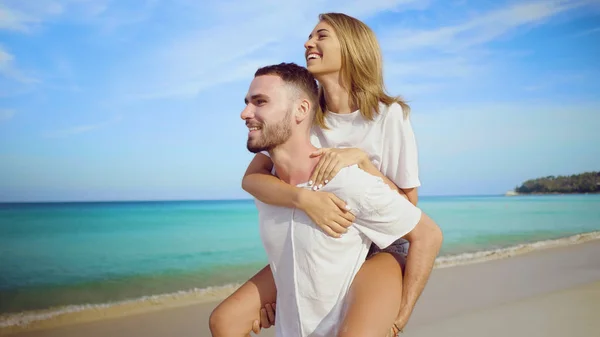 美丽快乐的情侣玩 做背驮在热带沙滩上海和天空背景 — 图库照片