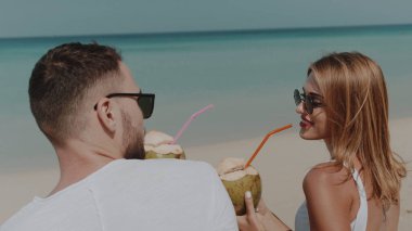 Genç mutlu içme Hindistan cevizi sütü tropik sahilde güneşli yaz tatili sırasında çift.