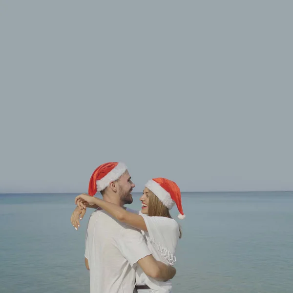 圣诞节美丽的海滩情侣戴着圣诞老人的帽子在夏天的阳光下在冬季假期的热带旅游目的地度假 — 图库照片