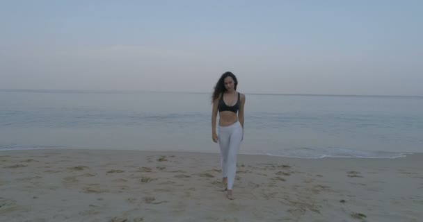 朝の練習後砂浜の上を歩いて美しい少女の空撮 — ストック動画