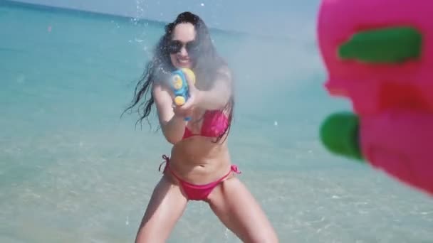 美しい少女水鉄砲水銃 スローモーションのビデオでピンクのビキニとサングラスで美しい笑みを浮かべて少女の一人称ビュー水しぶき — ストック動画