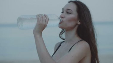 Güzel kız jogger İçmesuyu kum plajındaki / güzel kumlu plaj - ağır çekimde video sabah koşu sonra kız jogger içme suyu