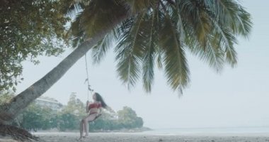 Güzel kız plajda / güzel salıncakta rahatlatıcı mayo - ağır çekimde video tropik sahilde salıncak üzerinde rahatlatıcı genç kız