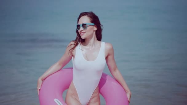 美丽的女孩与充气环在暑假期间 美丽的年轻女子泳装和太阳镜与粉红色充气环在海水中乐趣 享受阳光明媚的夏日在她的海滩热带假日 视频慢动作 — 图库视频影像