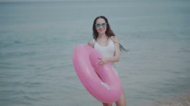 Güzel genç kız şişme yüzüklü yaz tatilinde / güzel yaz günü onu plaj tropikal tatil güneşli genç kadının mayo ve deniz suda eğlenmek pembe şişme halka ile güneş gözlüğü