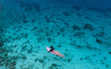 Hava dron görünümü güzel genç kadının mayo ve güneş gözlüğü şaşırtıcı berrak Denizi suda onun tatil keyfini pembe surfboard ile