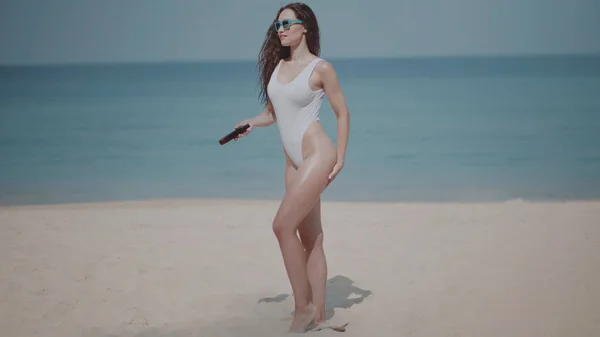 海と空の背景の上の夏の休暇中に熱帯の砂浜のビーチで体上日焼け止めローション日焼けオイルを適用する水着で美しい少女 — ストック写真