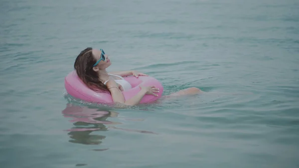 幸せな若い美人水着とサングラスに海の水で楽しいピンクのインフレータブル リングで彼女のビーチの熱帯休日の日当たりの良い夏の日を楽しんで — ストック写真