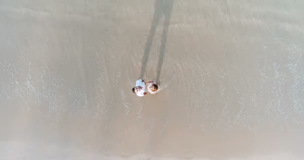 Beau couple en vacances / Top vue de drone de couple souriant sur la plage tropicale de sable avec des vagues de mer ondulantes 