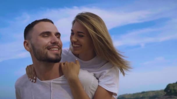 夏休み中に美しいカップル 美しい幸せなカップルのクローズ アップ楽しんで 空の背景 スローモーションのビデオ上で熱帯の砂浜でピギーバックを行う — ストック動画