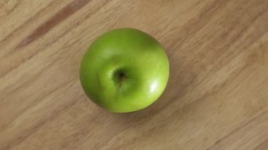 Ahşap plaka üzerinde yeşil elma / Top ahşap plaka üzerinde dönen lezzetli yeşil elma görünümünü