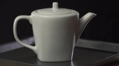 Beyaz porselen çaydanlık çaydanlık / beyaz porselen çaydanlık çaydanlık Closeup iplik tepsiye siyah arka plan üzerinde