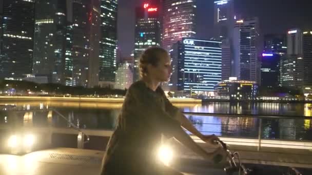 快乐的女人在她的自行车晚上 迷人的快乐的女人享受骑自行车通过城市在夜间 — 图库视频影像