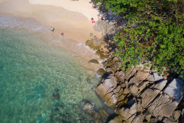 Turkuaz deniz yüzeyinin üzerinde taşlı ve kayalıklı hava aracı görüntüsü.