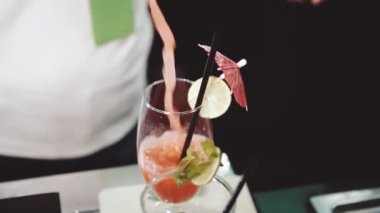 Bardaki kadın barmen tarafından bardağa kokteyl döküldü. Ağır çekimde video.