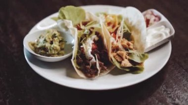 Guacamole, pico de gallo ve ekşi krema sosuyla servis edilen tavuk, peynir ve biftekli taco. Yavaş çekimde video.