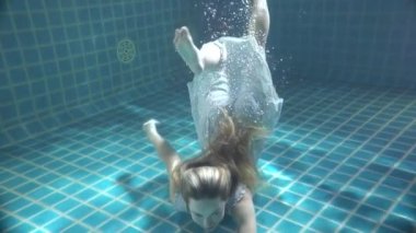 Suyun altında yüzen uzun kızıl saçlı güzel bir kadın. Ağır çekimde video.