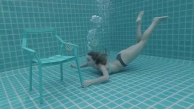 Suyun altında yüzen uzun kızıl saçlı güzel bir kadın. Ağır çekimde video.