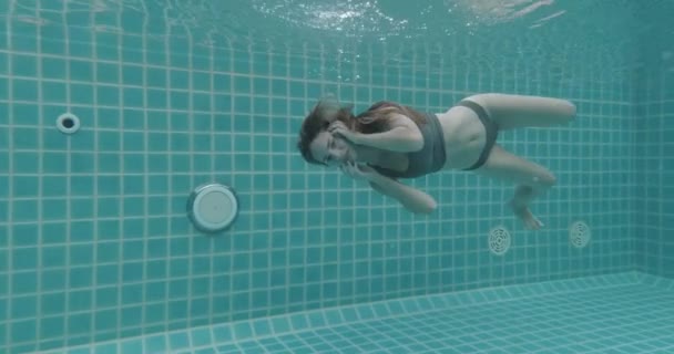 長い赤い髪の美しい女性がドレスで水中で泳いで ビデオをスローモーションで — ストック動画