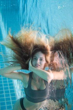 Uzun kızıl saçlı, bikinili güzel bir kadın.