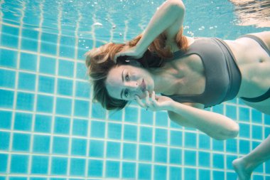 Uzun kızıl saçlı, bikinili güzel bir kadın.