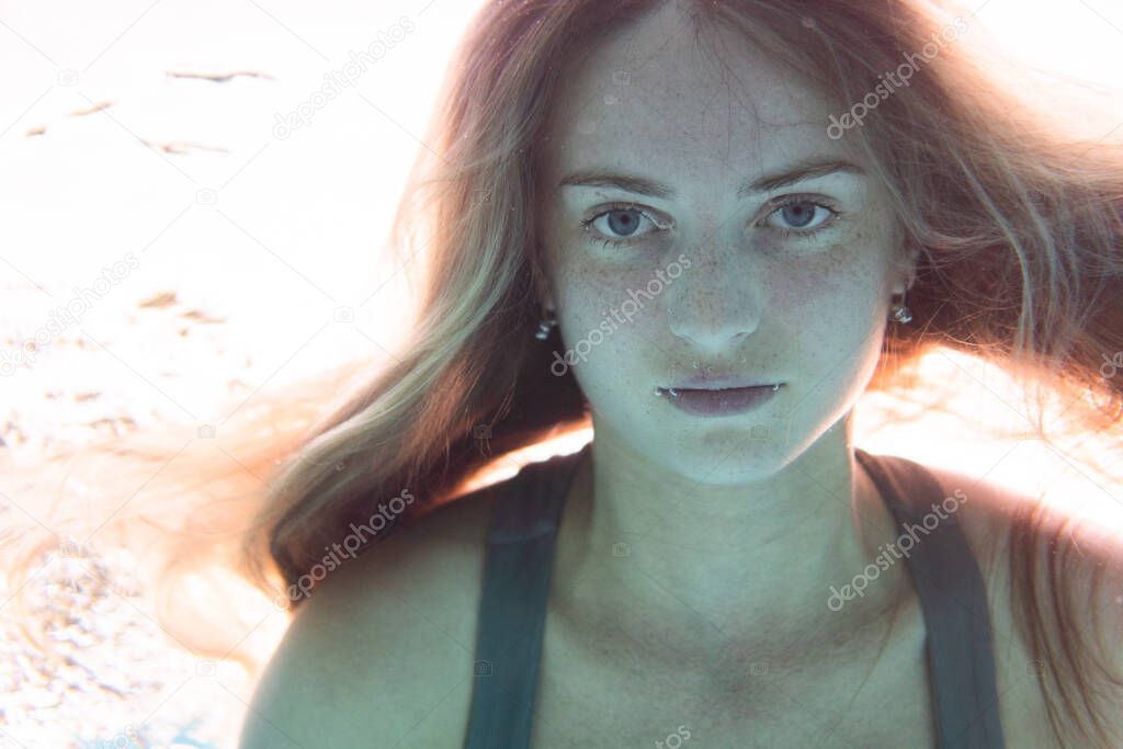 Closeup face of beautiful woman swimming underwater