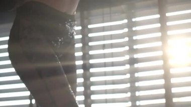 Siyah dantelli pantolon giyen, pencerenin üzerinde dans eden, arka planda perdelerle dans eden seksi kadının yakın çekim bacakları. Yavaş çekimde video.