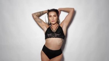 Stüdyoda beyaz duvar arkasında dans eden siyah iç çamaşırlı güzel bir akrobatik. Ağır çekimde video.