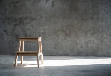 Stüdyoda boş ahşap bir merdiven var. Duvarın arkasında, bir taraftan güneş ışığı var.